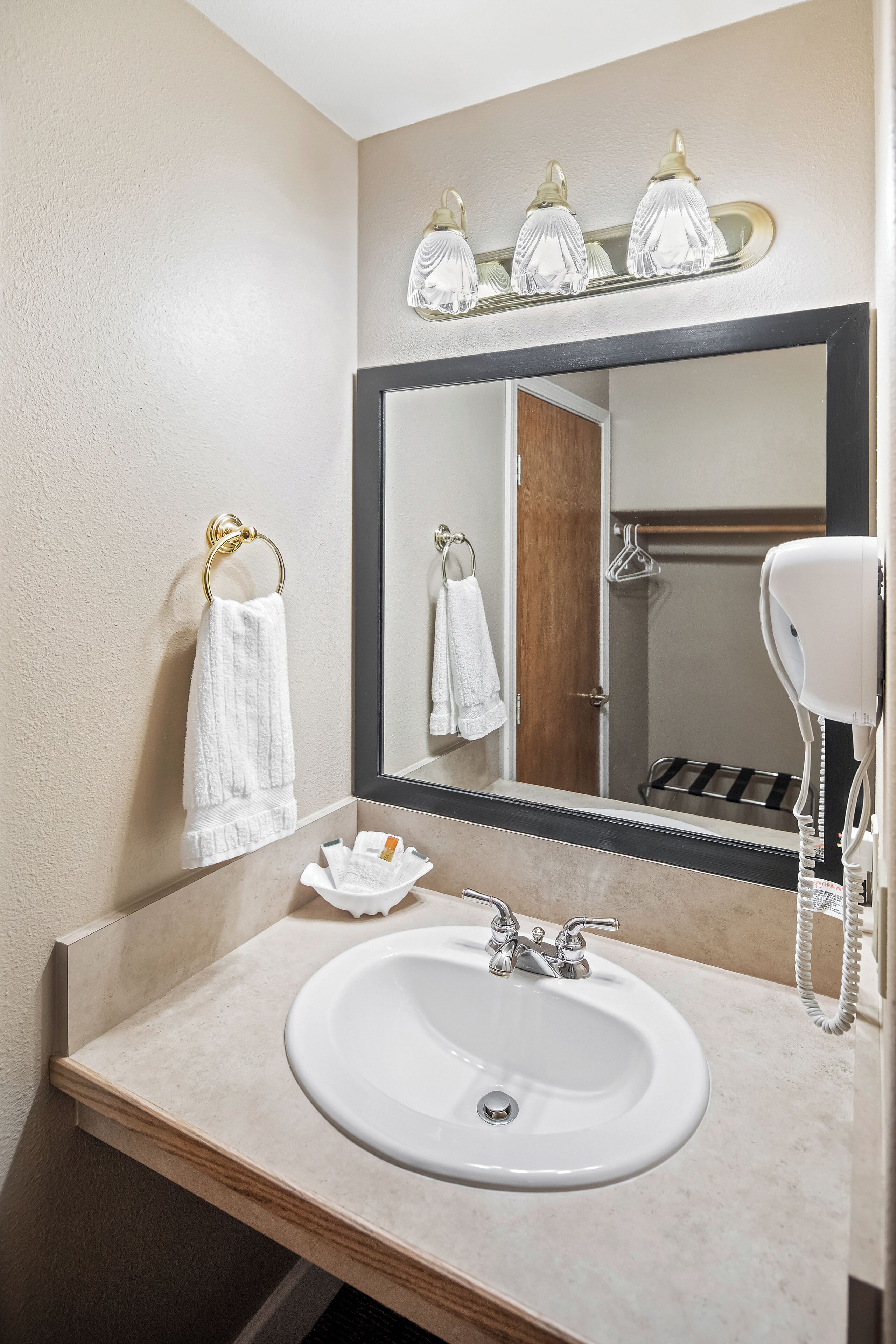 A bathroom with a sink, mirror, towel rack, and hairdryer.