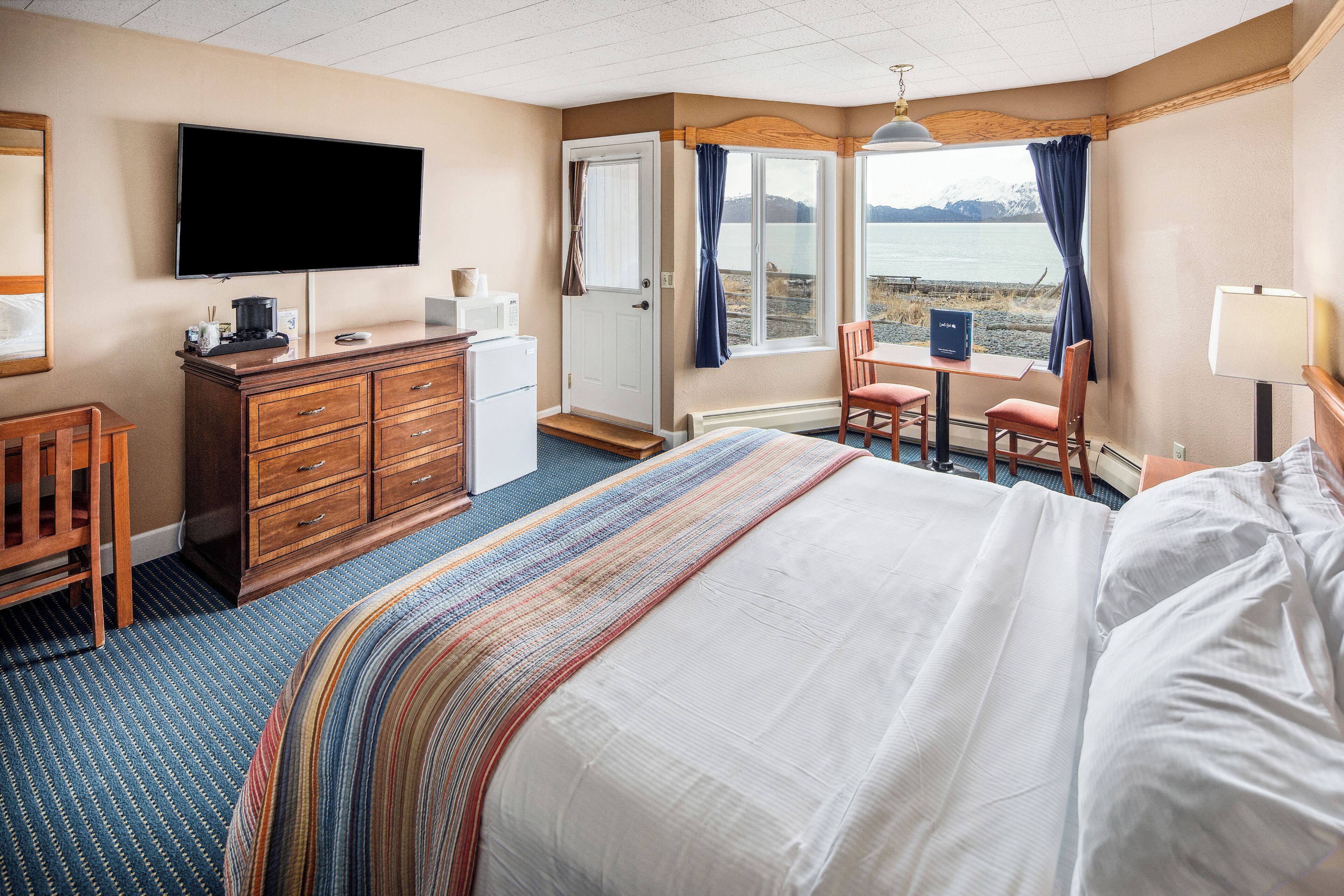 Une chambre d’hôtel équipée d’un lit, d’un bureau, d’une télévision, d’une commode et d’une fenêtre donnant sur l’eau.