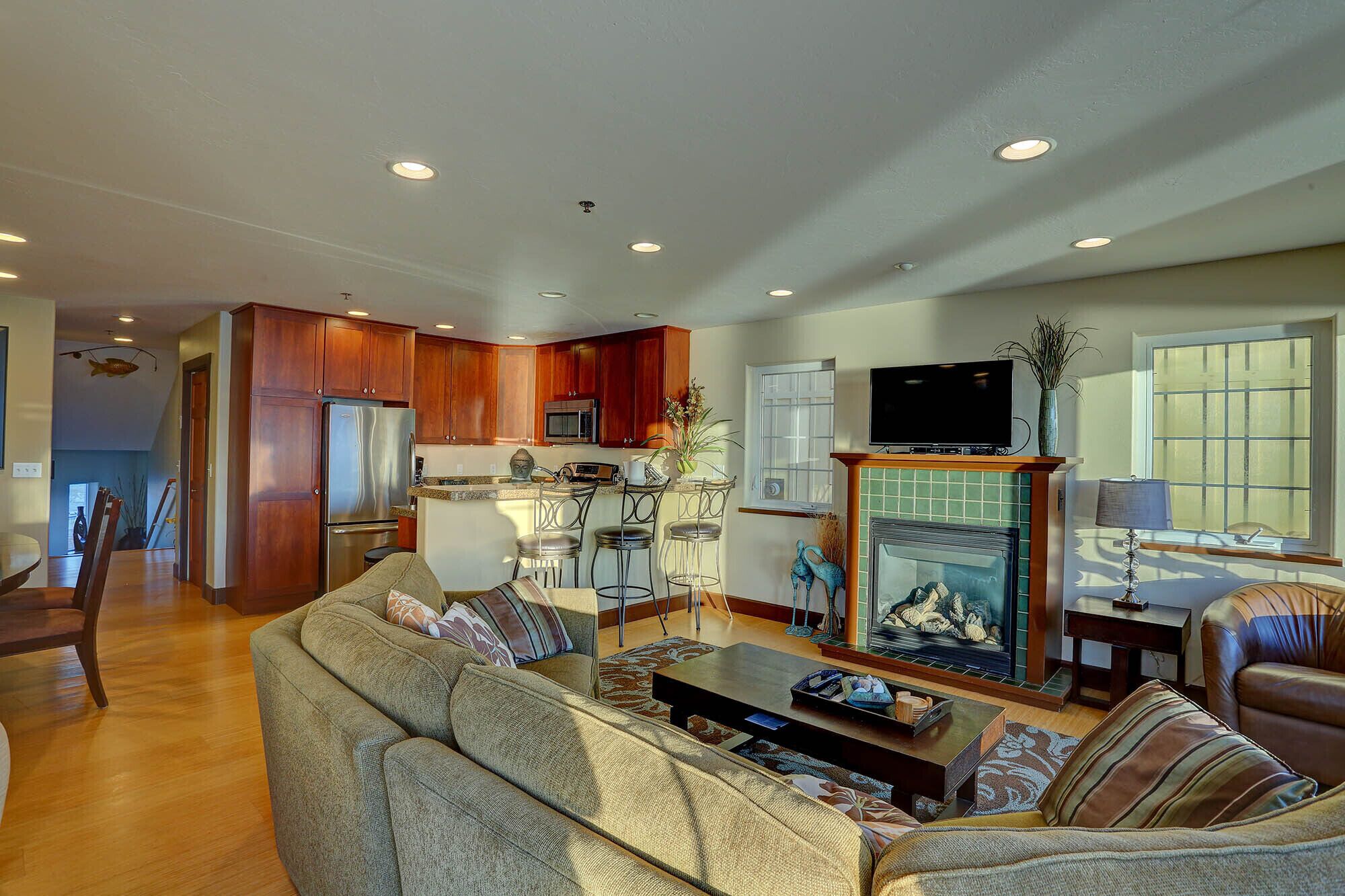 A spacious living room with a fireplace, a kitchen area with wooden cabinets, and a dining area with a table and chairs.