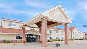 A hotel with a covered entrance, brick pillars, and a sign indicating it is an American hotel. - AmericInn by Wyndham Manitowoc (Manitowoc)