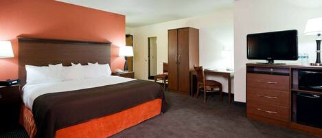 A hotel room with a bed, desk, TV, and wardrobe.