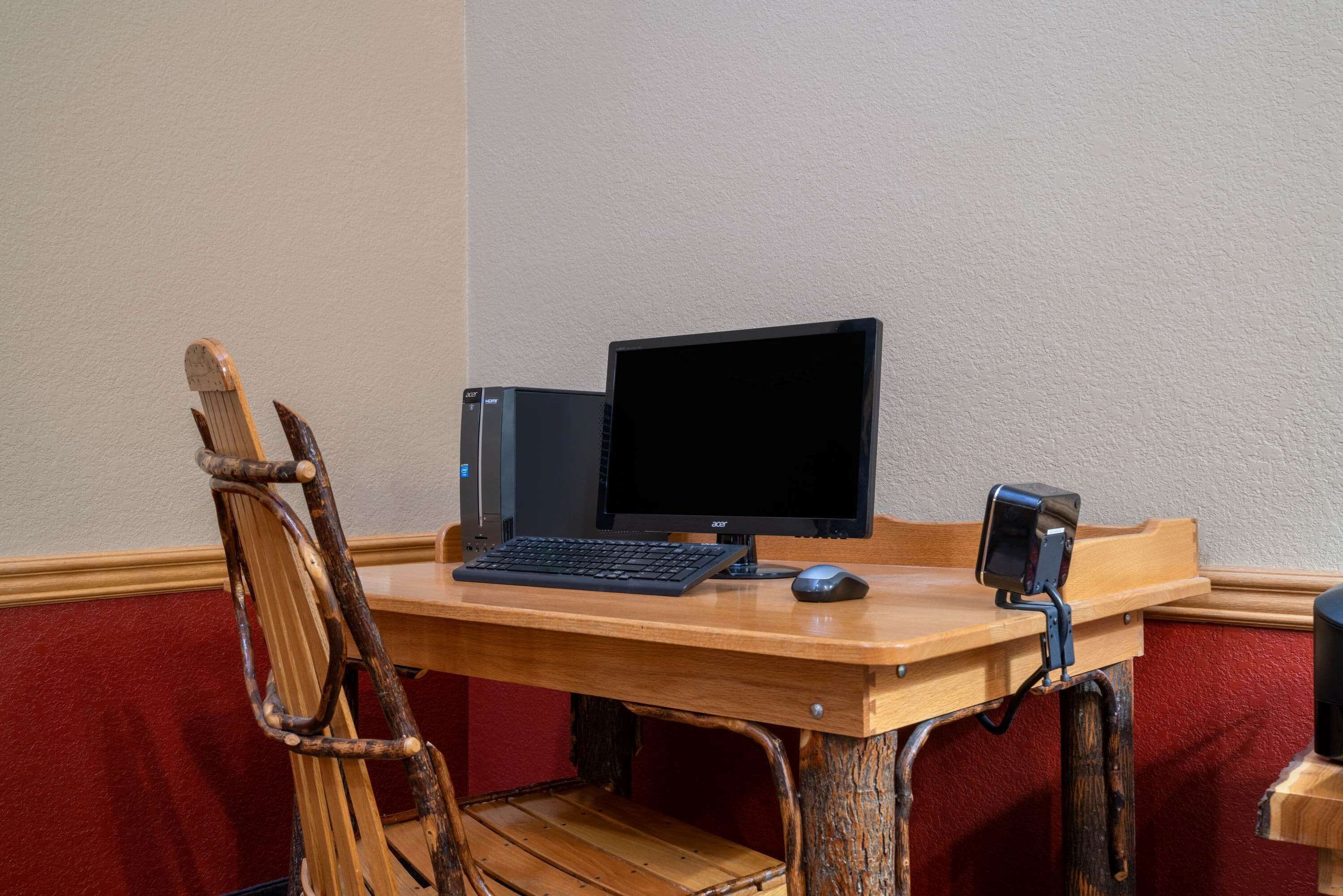 A wooden desk with a computer setup including a monitor, keyboard, and mouse.