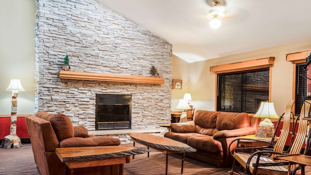 Una sala de estar acogedora con chimenea de piedra, sofás de cuero y una mesa de centro de madera.
