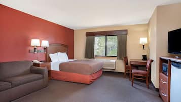 Een hotelkamer met een bed, een bureau, een stoel, een bank en een televisie.