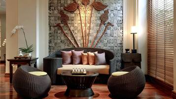 A modern living room with a sofa, two round wicker chairs, a coffee table, and decorative wall art.