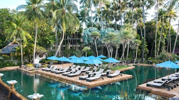 A pool area with lounge chairs and umbrellas, surrounded by palm trees.