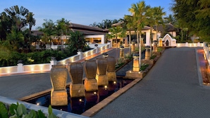 Un resort con piscina, palmeras y un puente.