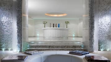 Una moderna zona de recepción con mostrador central, vitrinas de cristal y un área de descanso con libros.