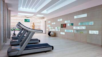A modern fitness center with treadmills, a wall-mounted TV, and various fitness-related displays.