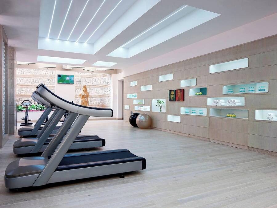 A modern fitness center with treadmills, a wall-mounted TV, and various fitness-related displays.