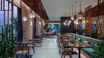 A modern restaurant with wooden accents, round pendant lights, and a view of palm trees.