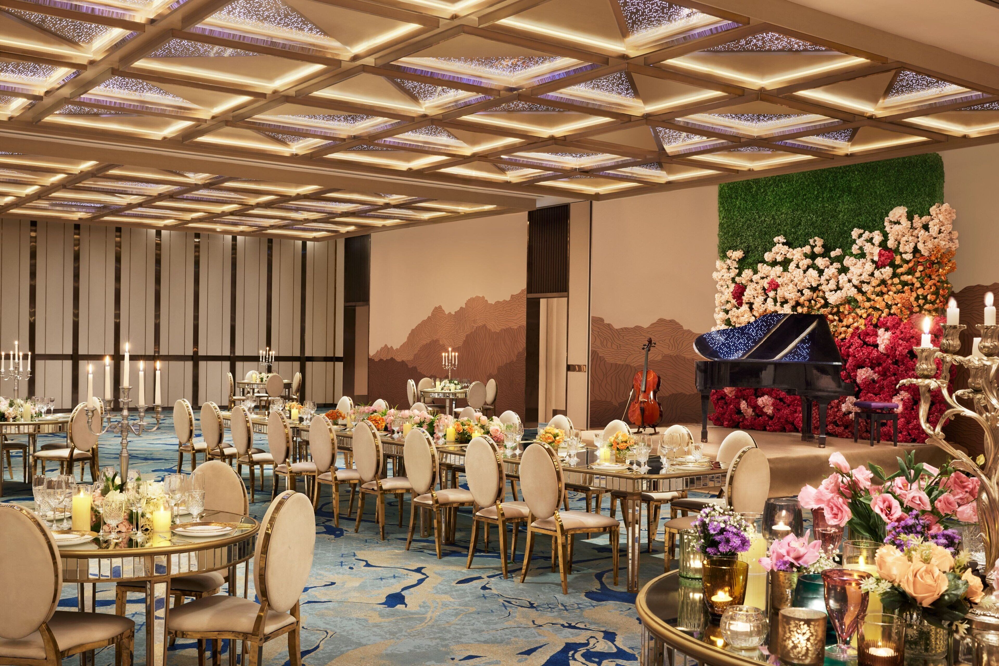 A banquet hall with round tables, chairs, and a stage with a piano.