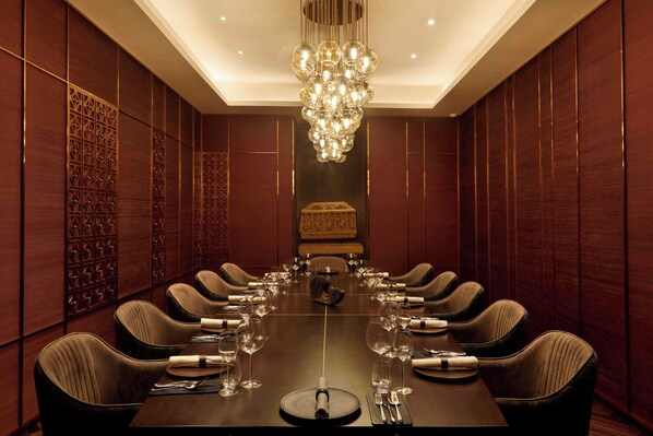 Un salón de conferencias con una larga mesa, múltiples sillas y un candelabro.