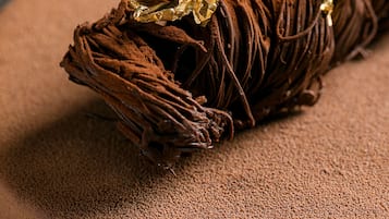 A chocolate cake with a textured surface and a decorative golden leaf on top.