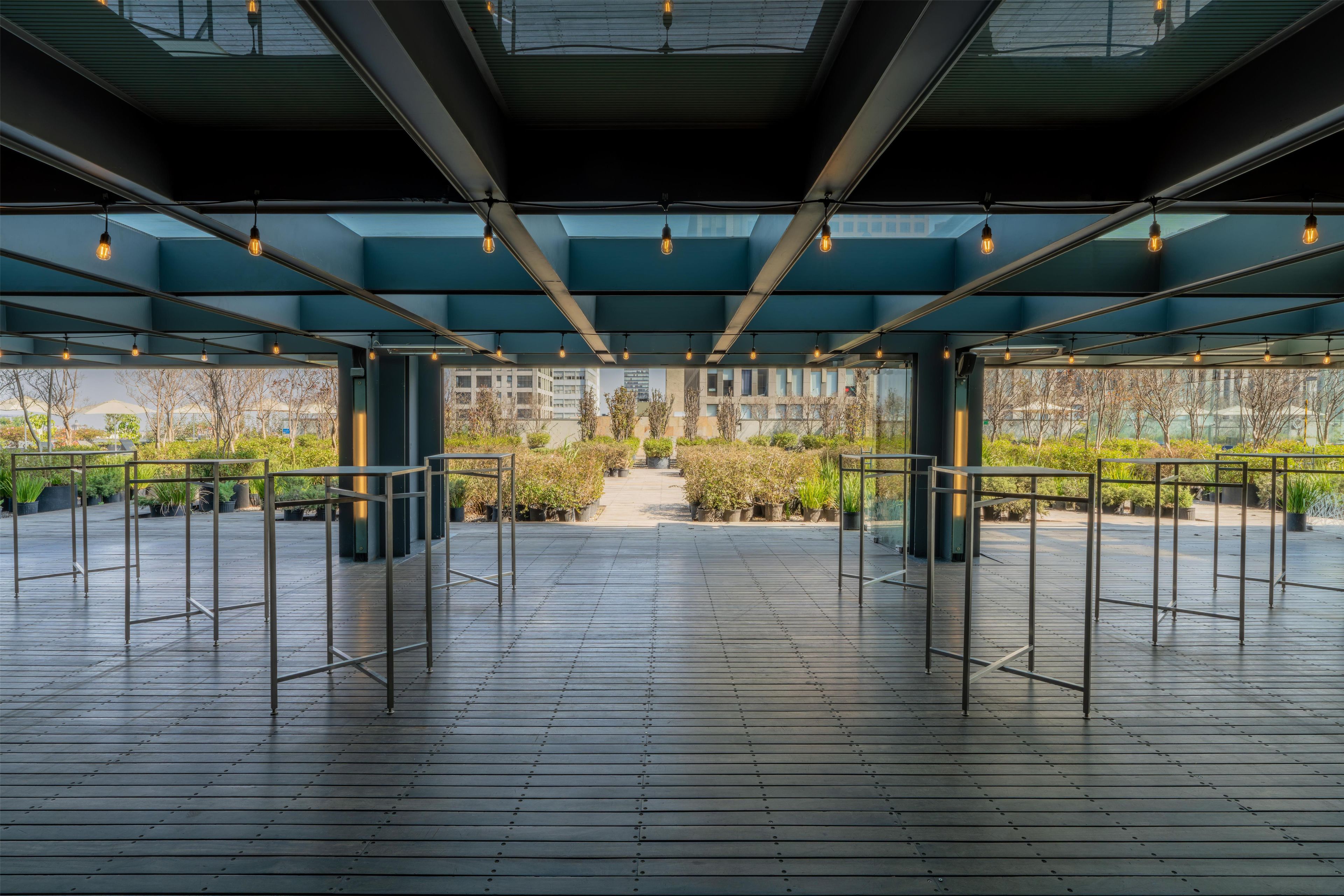 An indoor space with a wooden floor, metal railings, and a view of greenery outside.