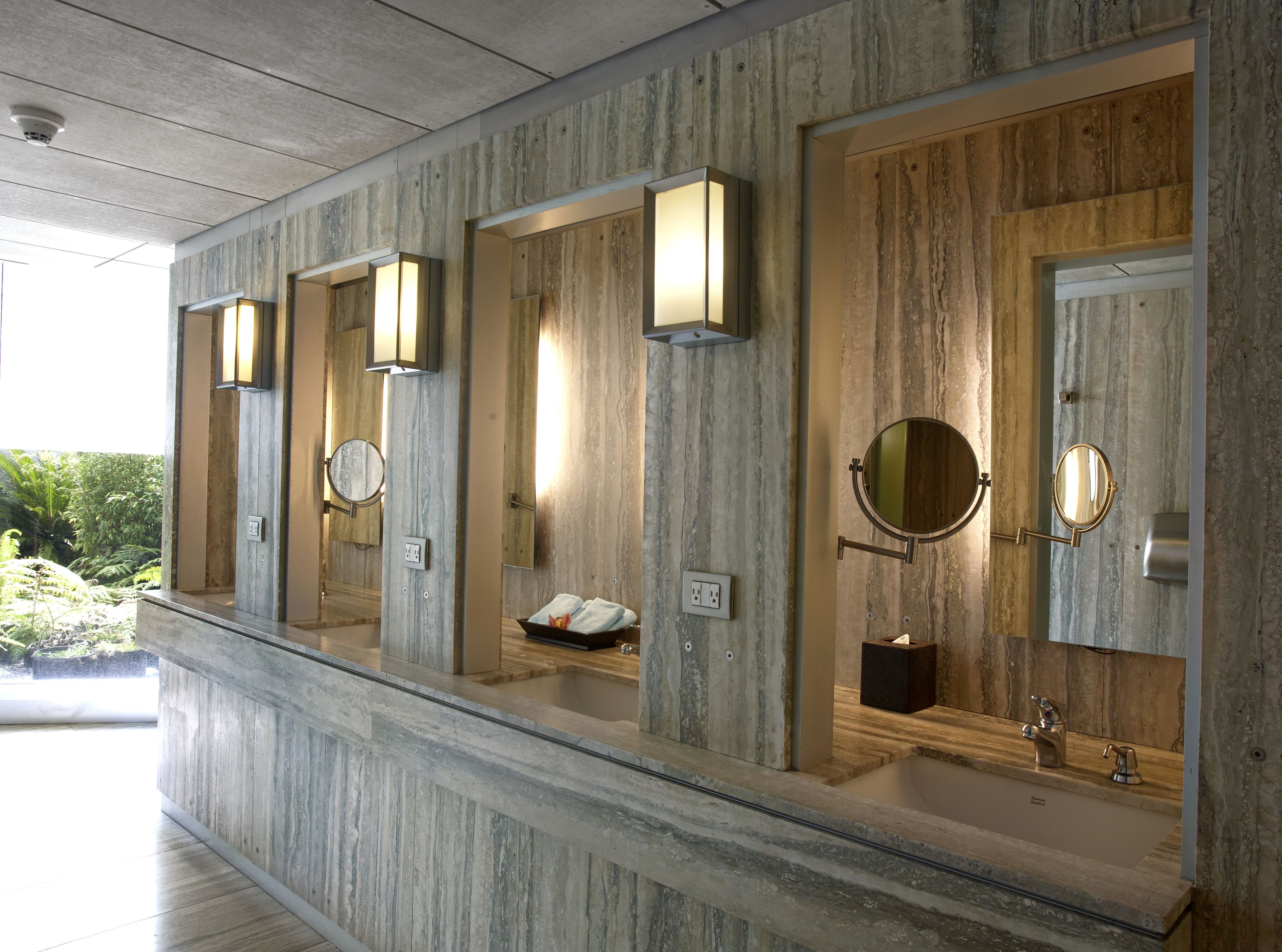 A row of modern bathrooms with marble countertops, built-in sinks, and wall-mounted mirrors.