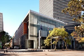 A modern building with a glass facade, a flagpole, and a street in front. - Hilton Mexico City Reforma (Mexico City)