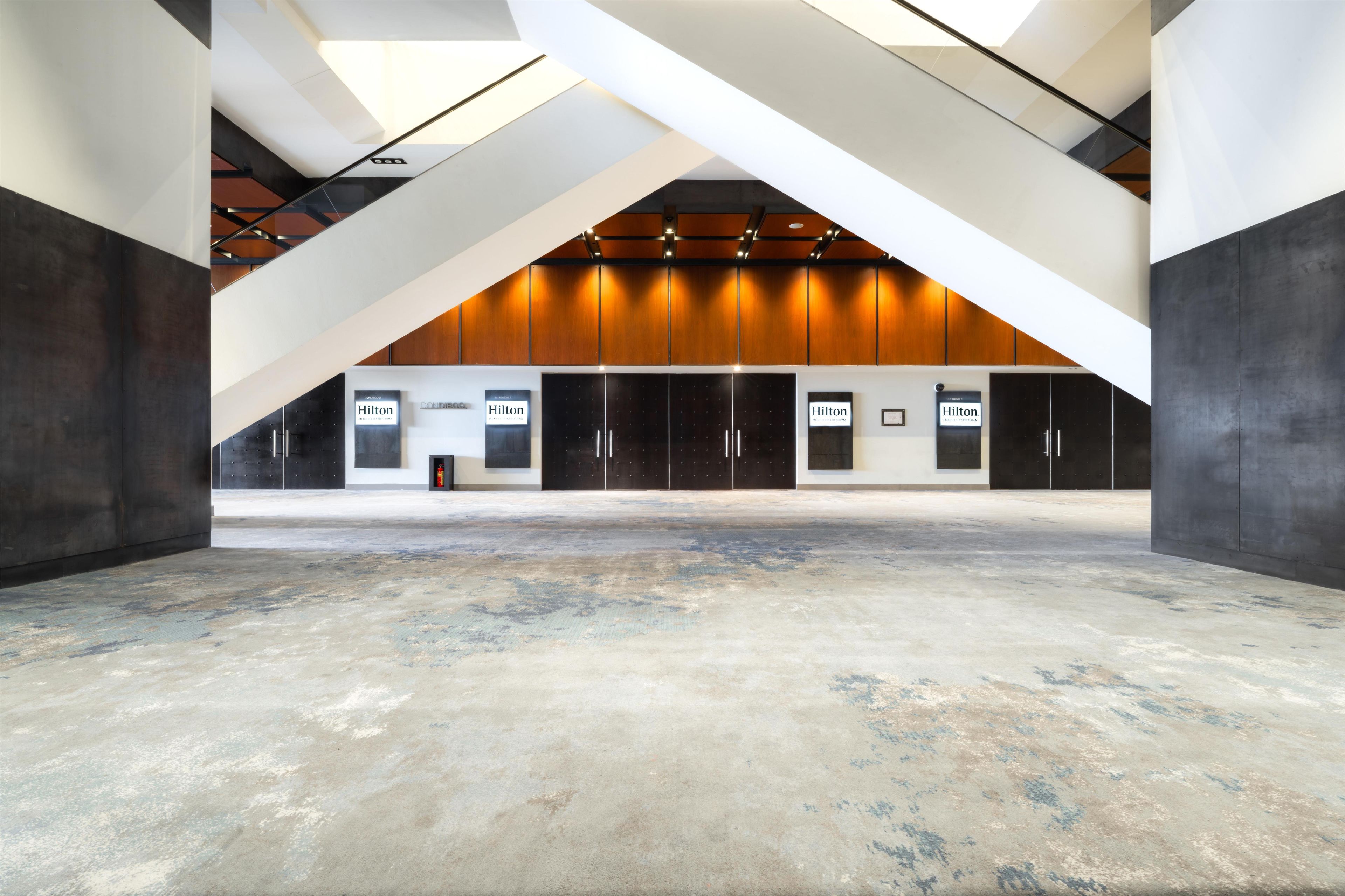 A spacious atrium with a high ceiling, exposed beams, and a central area with a fire extinguisher.