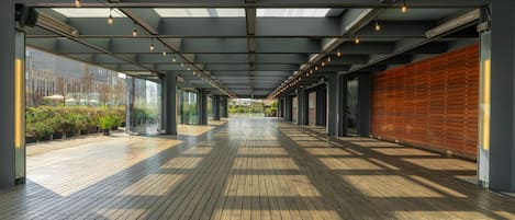 Un pasillo cubierto con piso de madera, vigas de metal y luces colgantes.