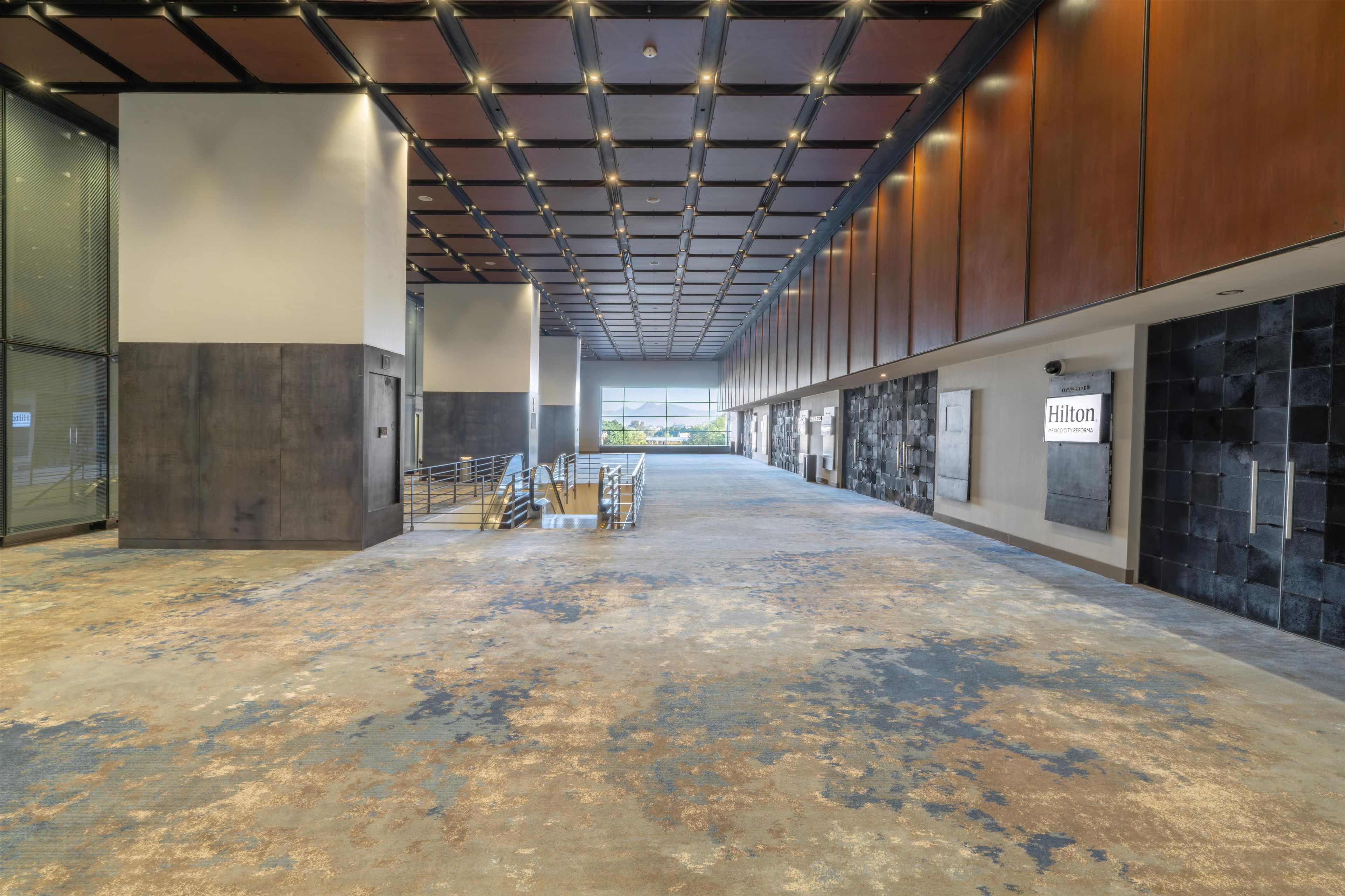 A spacious indoor area with a high ceiling, metal beams, and a view through a glass wall.