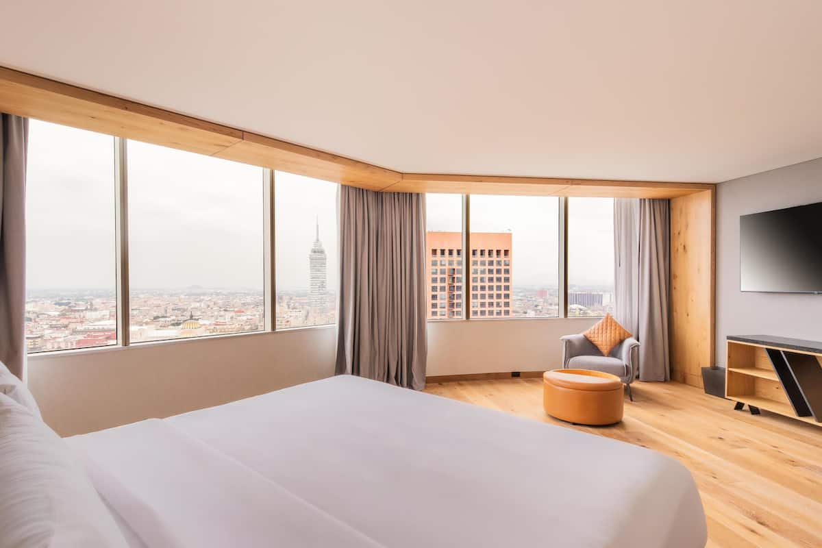Habitació d'hotel moderna amb un llit gran, zona de seients i televisió.