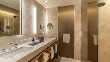 A modern bathroom with a large mirror, two sinks, a shower area, and a towel rack.