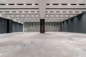Un espacio interior amplio con suelo de hormigón, iluminación empotrada y un pilar central.