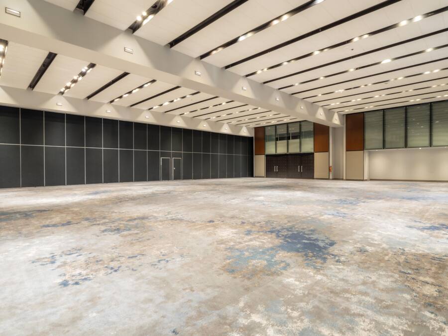 Un vaste espace intérieur doté d’un haut plafond, d’un éclairage encastré et d’un grand mur orné d’un motif en réseau.