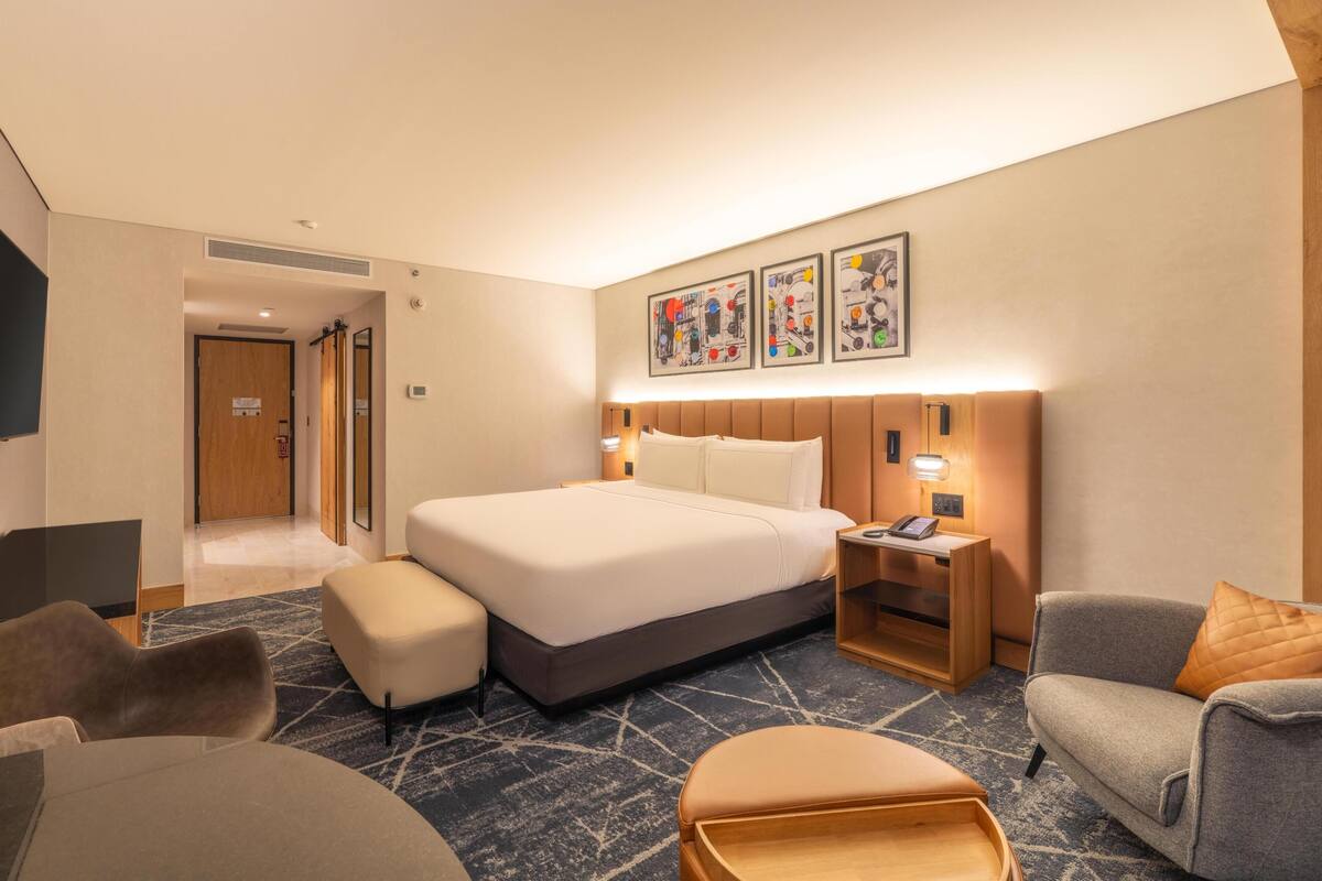 Habitació d'hotel amb llit, taules de nit, escriptori, cadira i sofà.