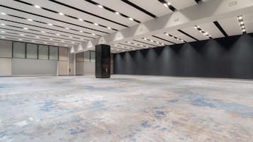 Un espacio interior amplio con techo alto, iluminación empotrada y suelo de hormigón.