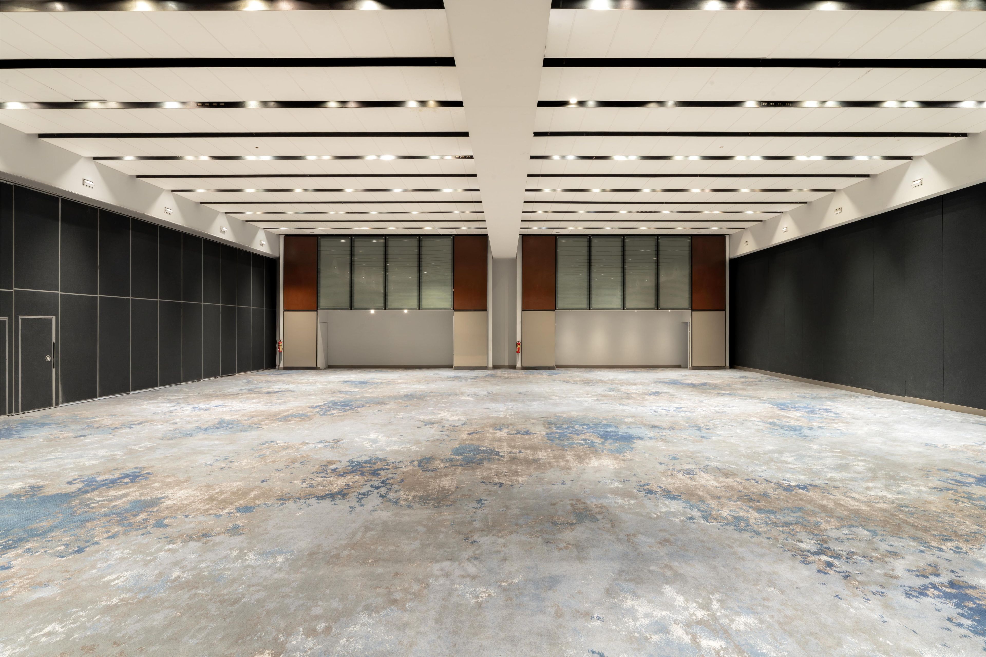 Un interior espacioso y moderno con techo alto, iluminación empotrada y suelo de concreto pulido.