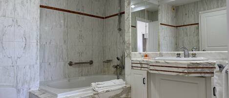 A modern bathroom with a marble sink, a bathtub, and a large mirror.