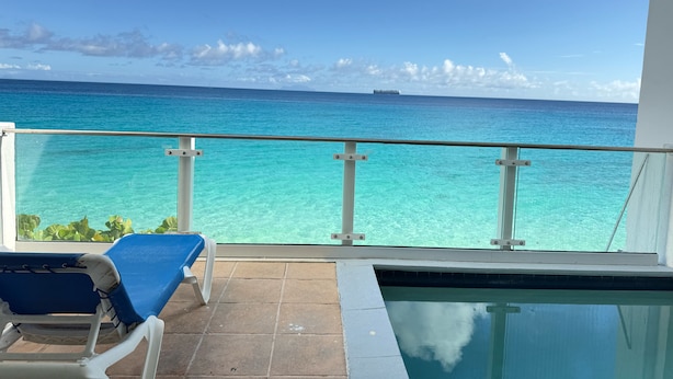A balcony with a pool, clear turquoise water, and a distant ship. - Sapphire Beach Club Resort (Lowlands)