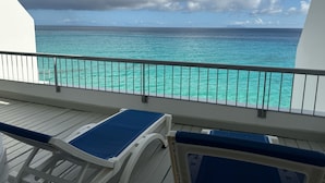 A deck with two lounge chairs and a railing overlooking turquoise ocean waters. - Sapphire Beach Club Resort (Lowlands)