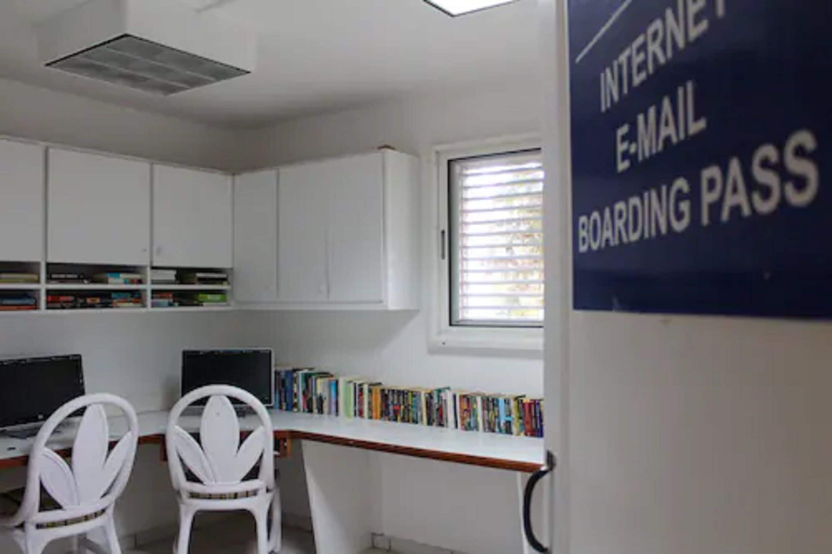 A library with white cabinets, two computer desks, and a window with blinds.