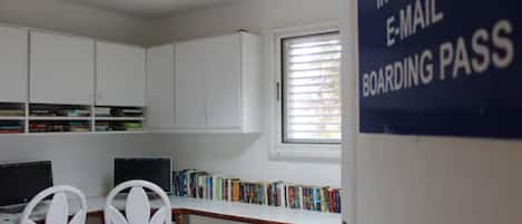 A library with white cabinets, two computer desks, and a window with blinds.
