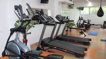 Un gimnasio con cintas de correr, bicicletas estáticas y equipamiento de ejercicio.