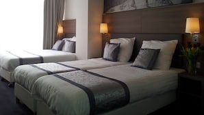 A hotel room with two beds, each with a headboard, bedside lamps, and a large framed picture on the wall. - The Concert Hotel (Amsterdam)