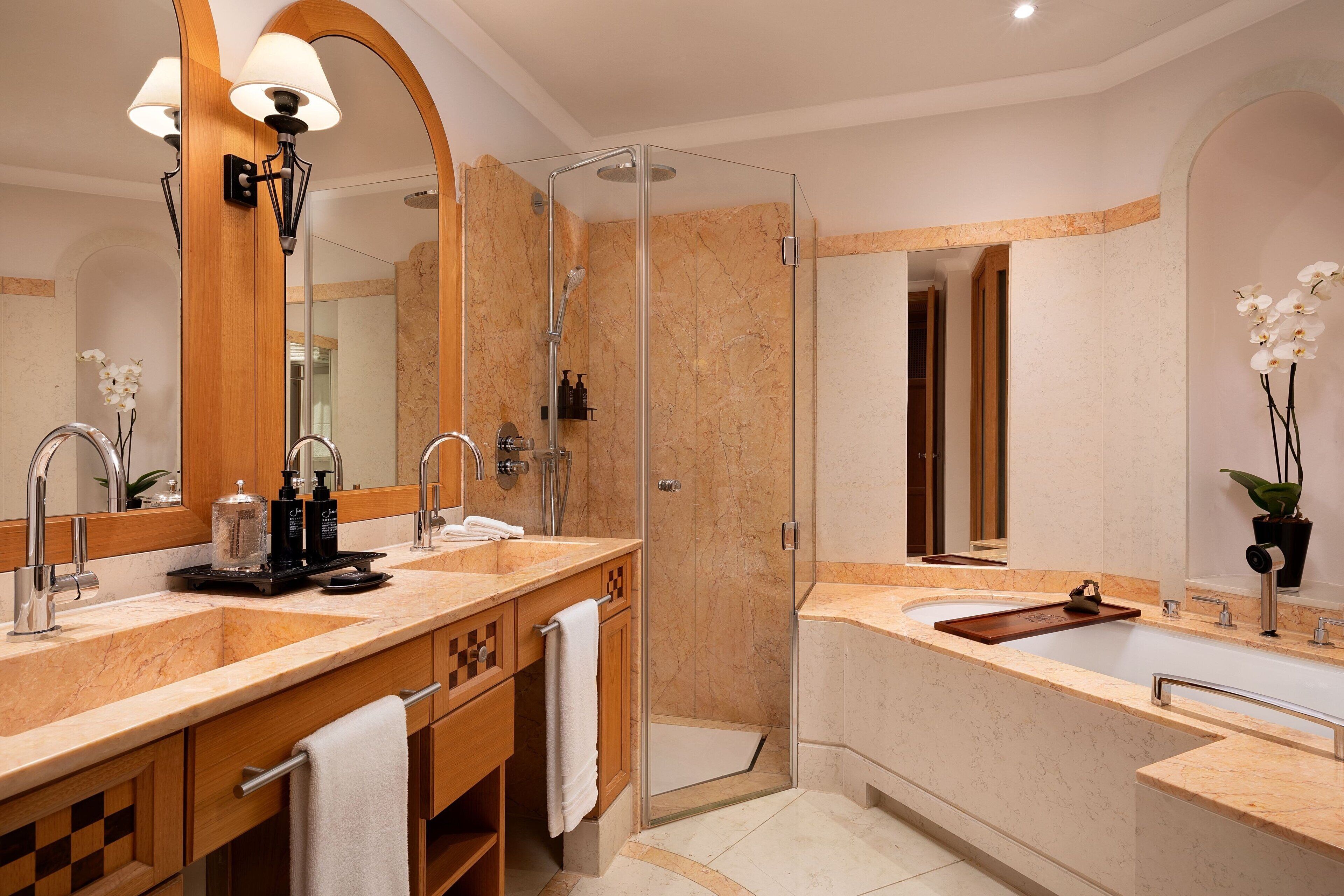 A modern bathroom with two sinks, a glass shower enclosure, and a large mirror.