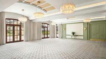 A spacious room with patterned carpet, large windows, and green doors.
