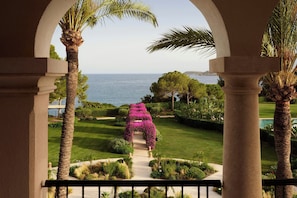 A view through an archway of a well-maintained garden with a pathway leading to a body of water. - The St. Regis Mardavall Mallorca Resort (Calvia)