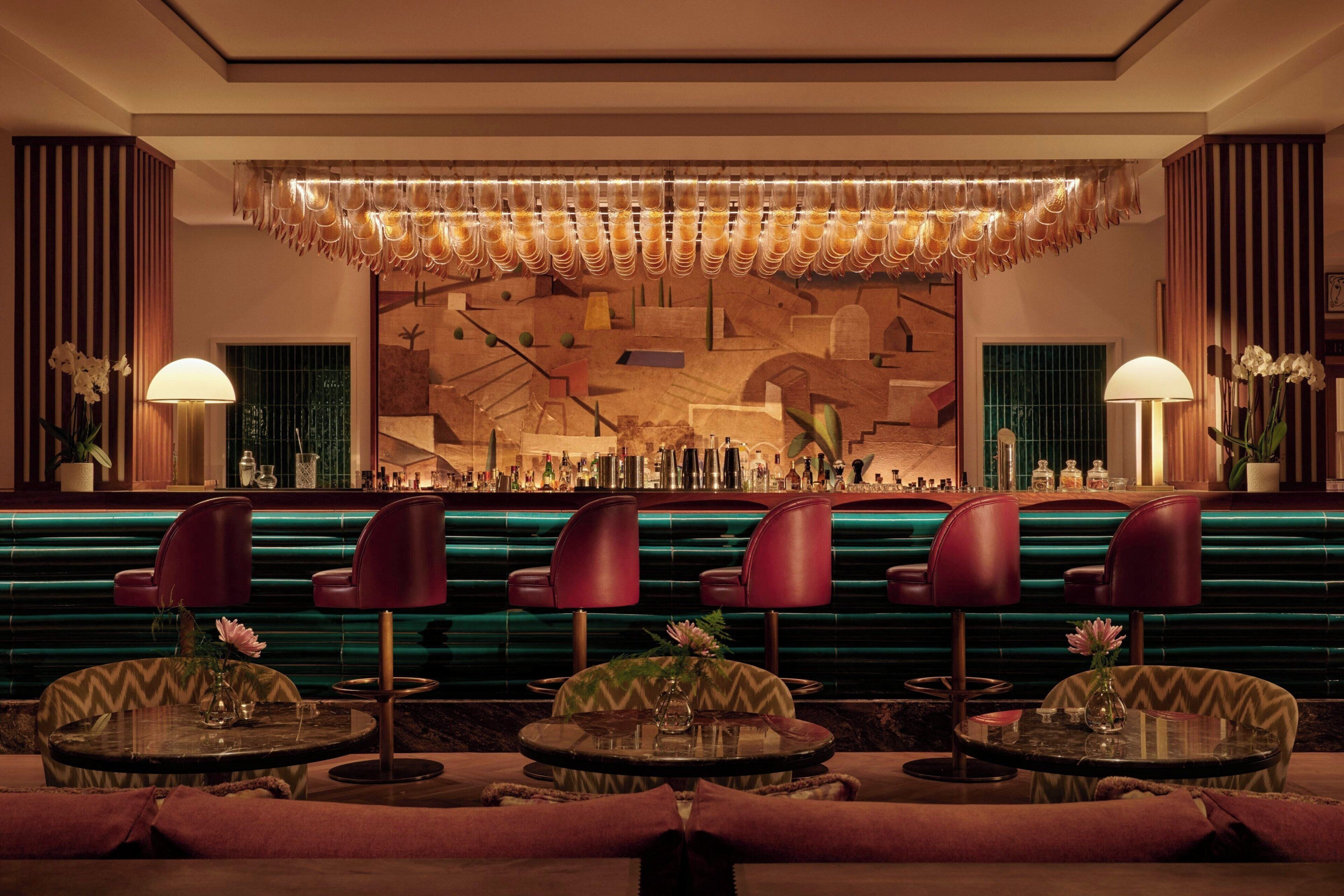 Una zona de bar con diseño moderno, que incluye una barra, diversas opciones de asiento y una pared decorativa.