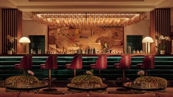 Una zona de bar con diseño moderno, que incluye una barra, diversas opciones de asiento y una pared decorativa.