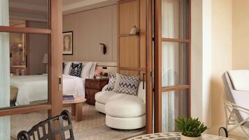 A hotel room with a bed, a seating area with a table, a chair, and a small potted plant.