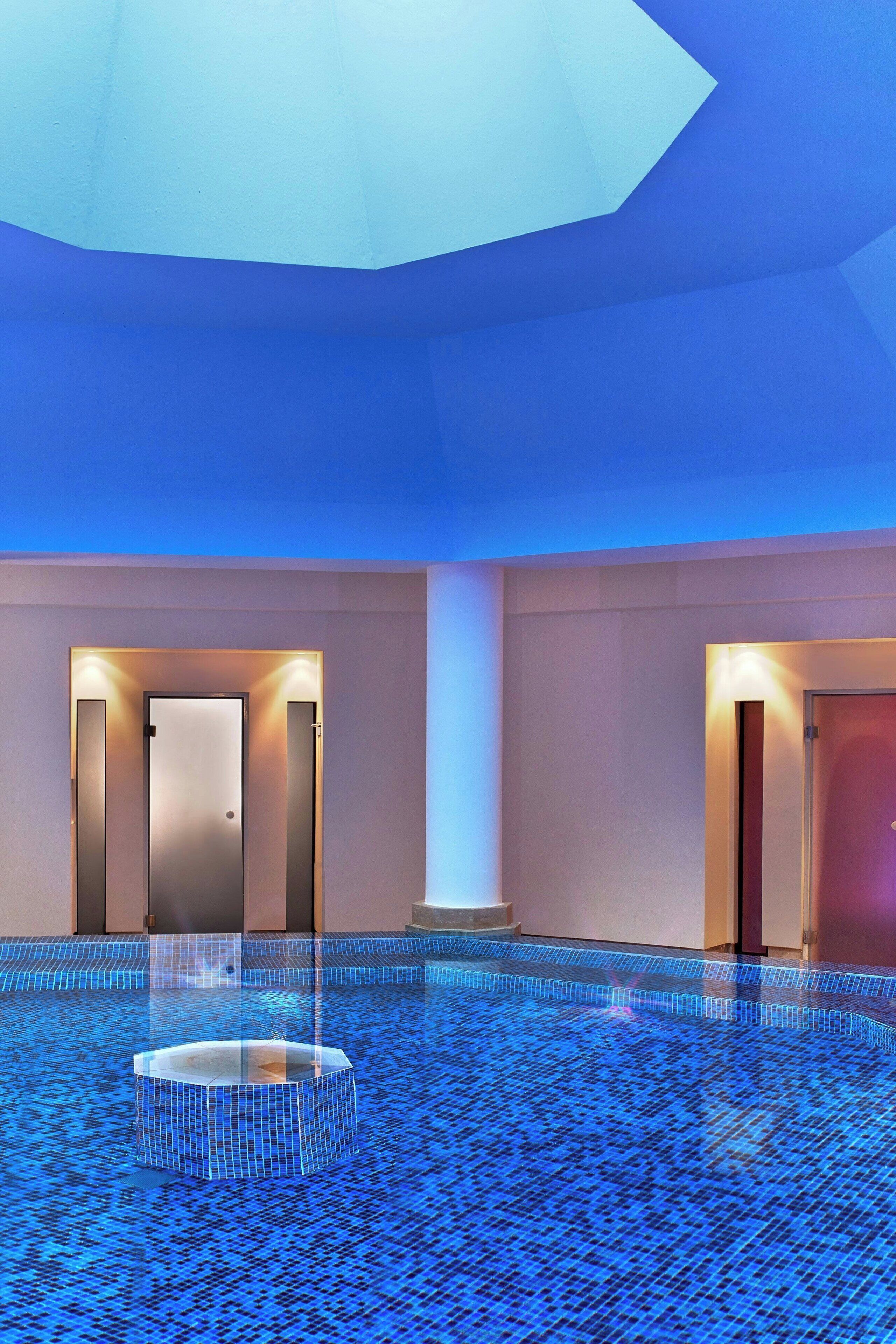A spacious indoor area with a tiled floor, two doors, and a central circular feature.
