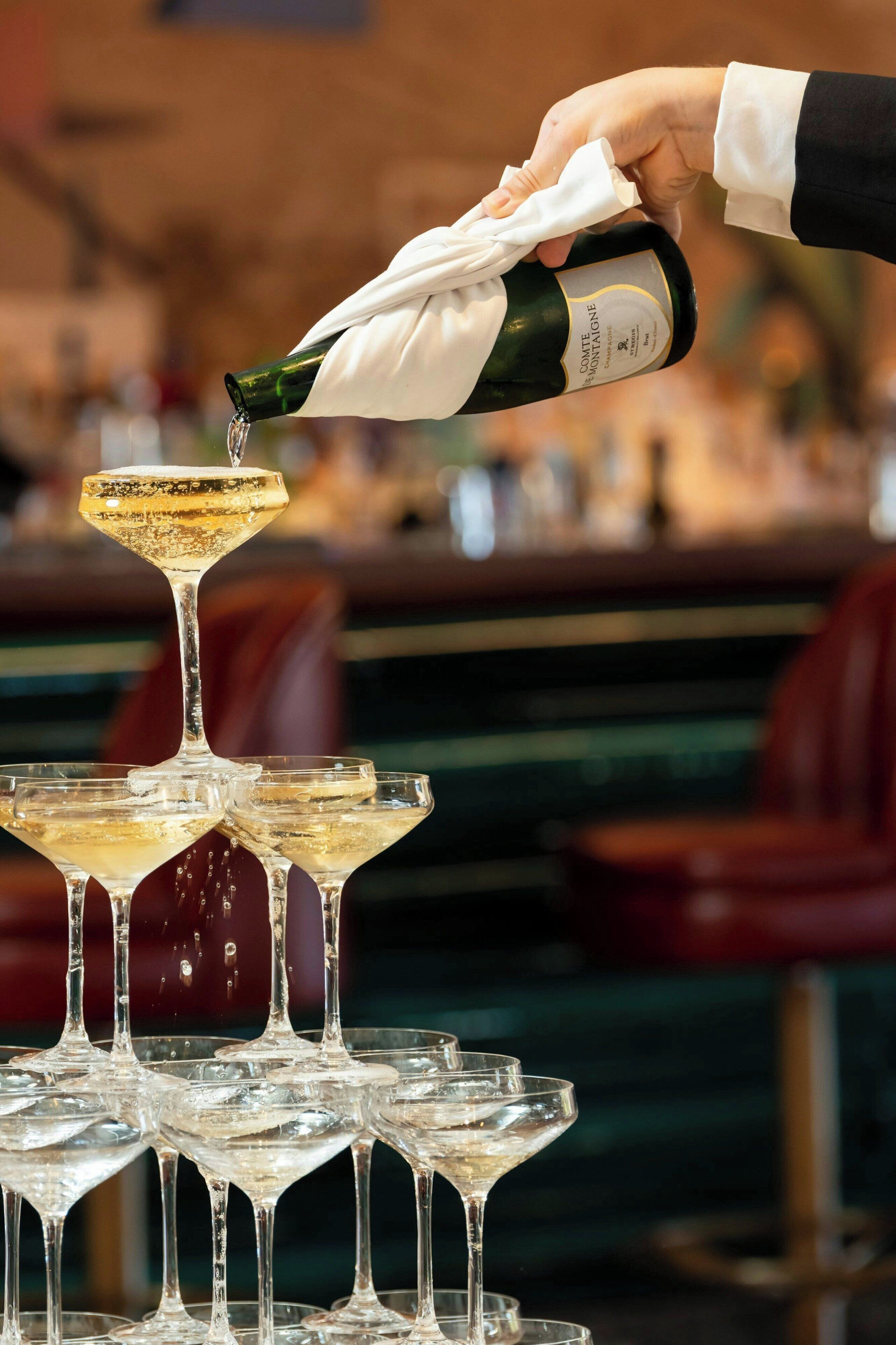 A hand pouring champagne into a glass.