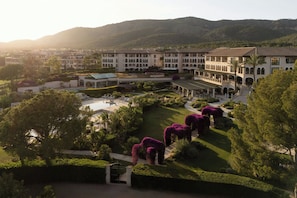 A large, multi-story hotel with a central courtyard, surrounded by lush greenery and hills. - The St. Regis Mardavall Mallorca Resort (Calvia)