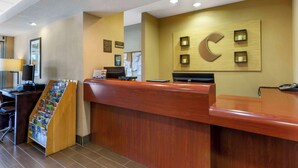 A reception desk with a wooden finish, a computer, and a magazine rack. - Comfort Inn Green Valley I-19 (Green Valley)
