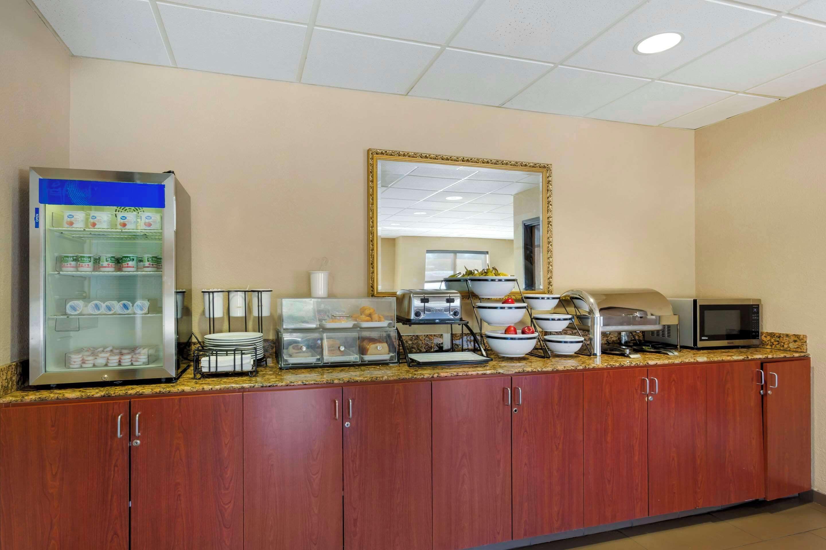 A kitchenette with a refrigerator, microwave, toaster, and various food containers.