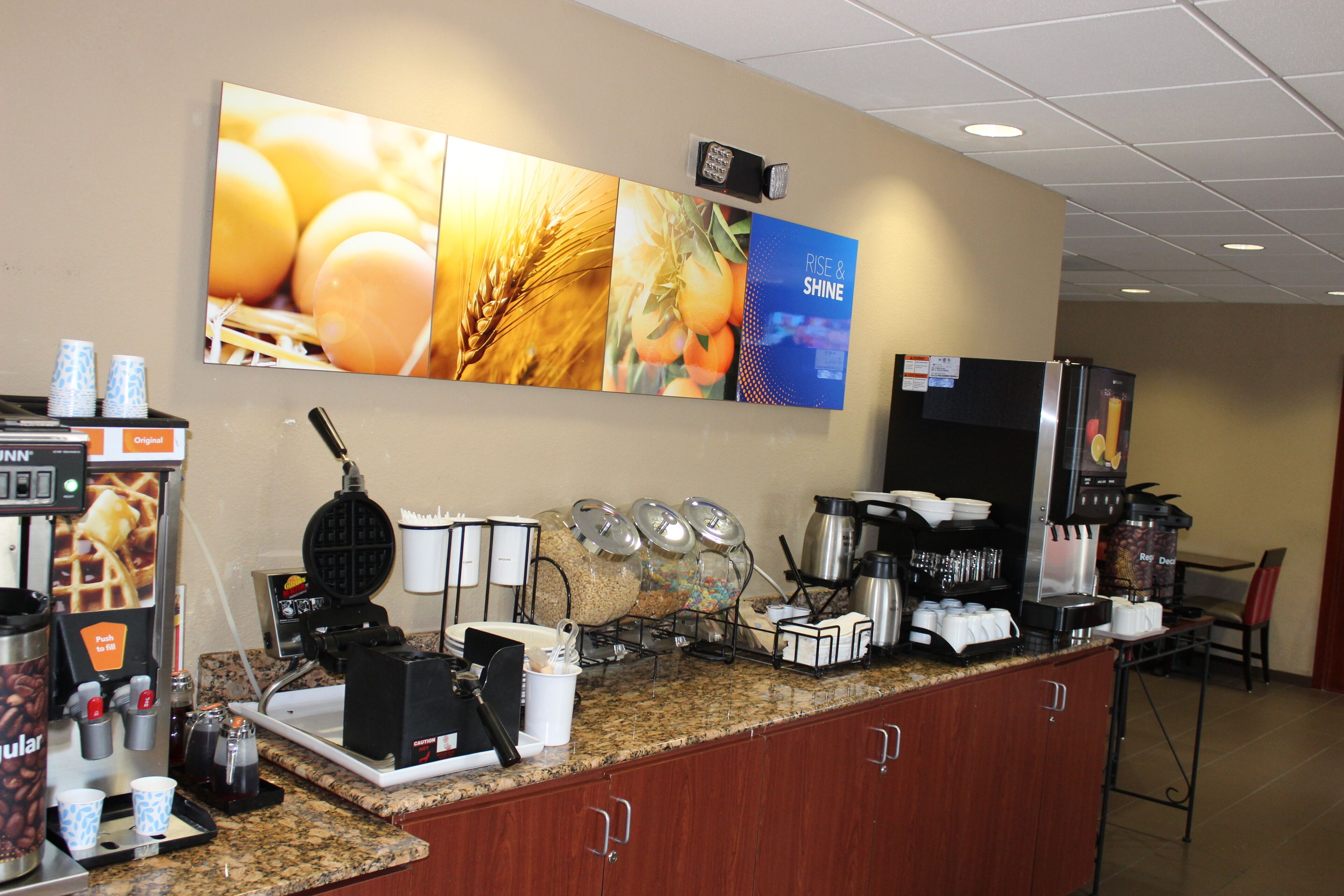 A breakfast bar with coffee machines, a waffle maker, and food dispensers.